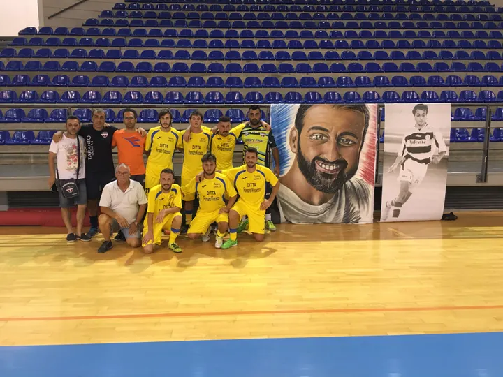 Una squadra in maglia gialla Morricella 10 al palazzetto, davanti allo stendardo Ciao Morris