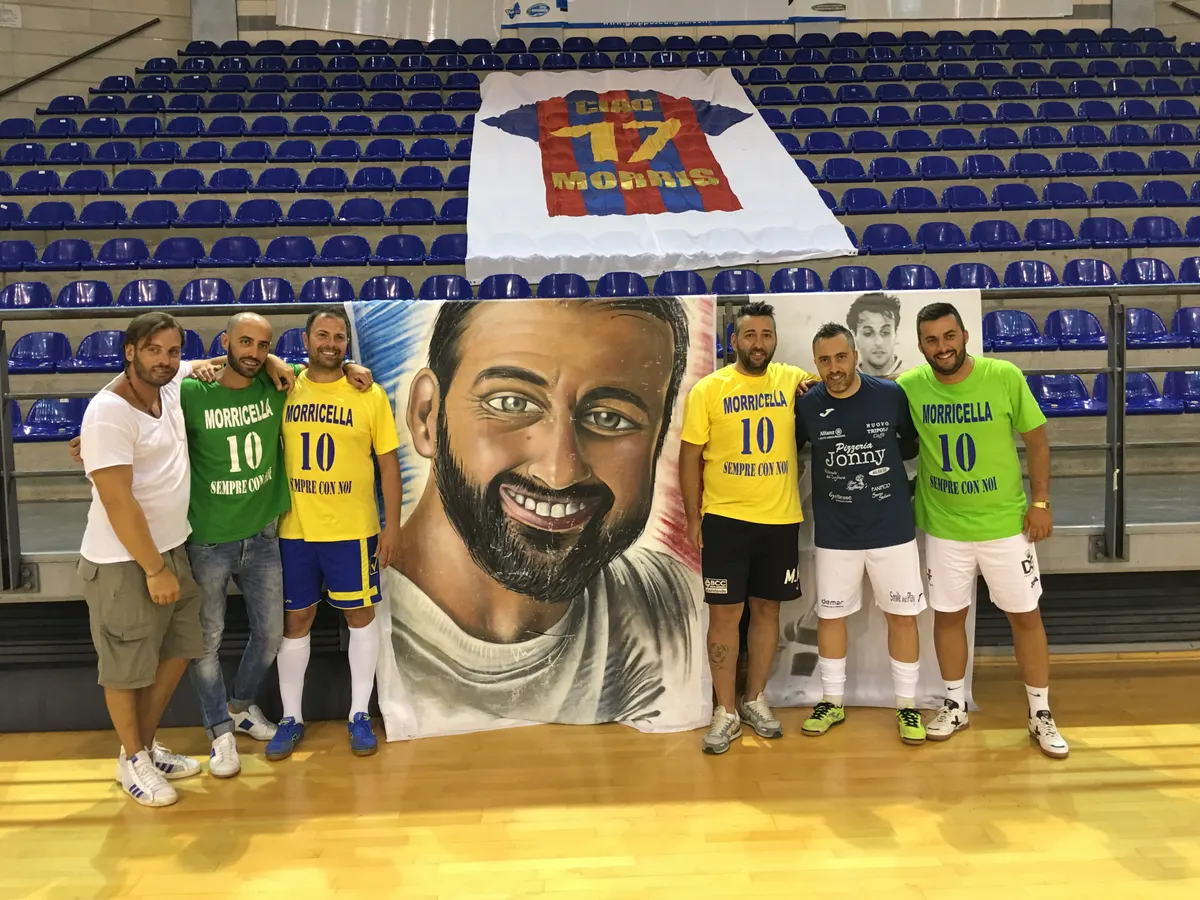 Un gruppo di amici con le maglie commemorative Morricella 10 davanti al grande ritratto dipinto di Alessandro Morricella