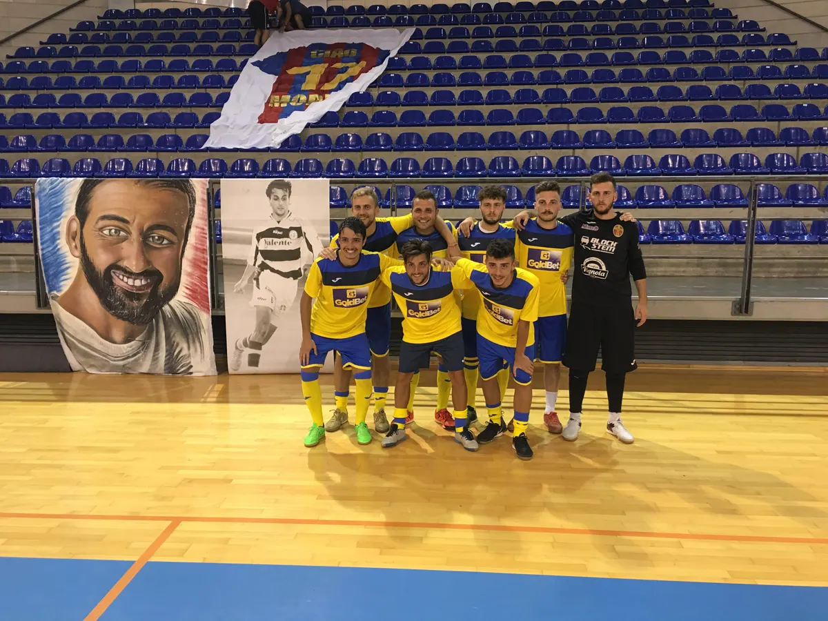 Una squadra al palazzetto, con il telo della maglia Ciao Morris appeso sugli spalti